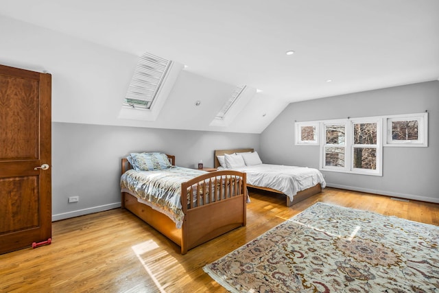 bedroom with light wood finished floors, baseboards, vaulted ceiling with skylight, and recessed lighting