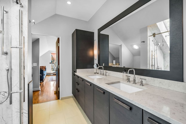 bathroom featuring a sink, double vanity, lofted ceiling, and a marble finish shower