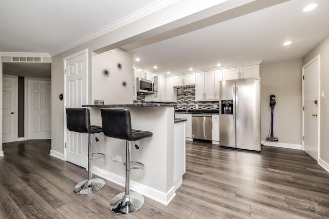 11102 S 84th Ave Unit 2B, Palos Hills, IL 60465 - kitchen with appliances with stainless steel finishes, white cabinetry, a kitchen bar, a sink, and dark wood-style floors