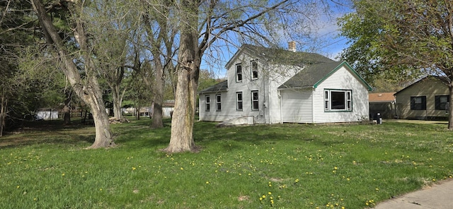 view of home's exterior featuring a lawn, a chimney, and a shingled roof