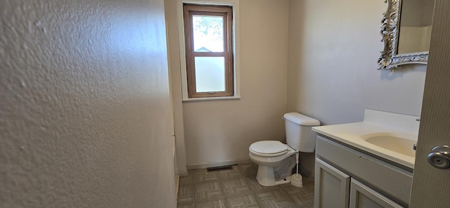 bathroom featuring vanity, toilet, baseboards, and visible vents