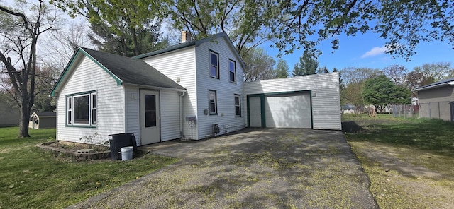 exterior space featuring aphalt driveway, a garage, and a chimney