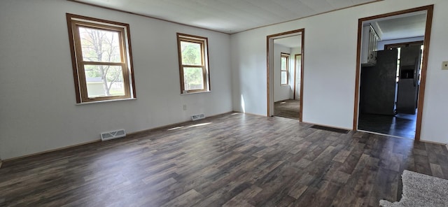 unfurnished room with baseboards, dark wood-type flooring, and visible vents