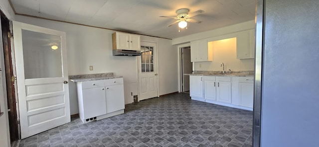 kitchen with under cabinet range hood, ceiling fan, a sink, and white cabinets