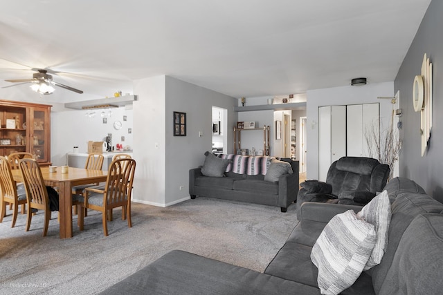carpeted living room featuring baseboards and ceiling fan
