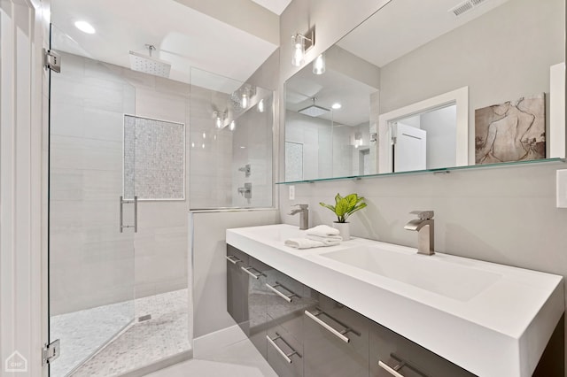 full bath featuring a sink, double vanity, a shower stall, and visible vents