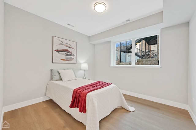 bedroom featuring baseboards, visible vents, and wood finished floors