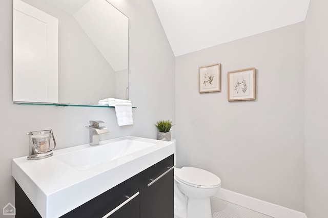 bathroom featuring toilet, baseboards, tile patterned floors, vanity, and vaulted ceiling