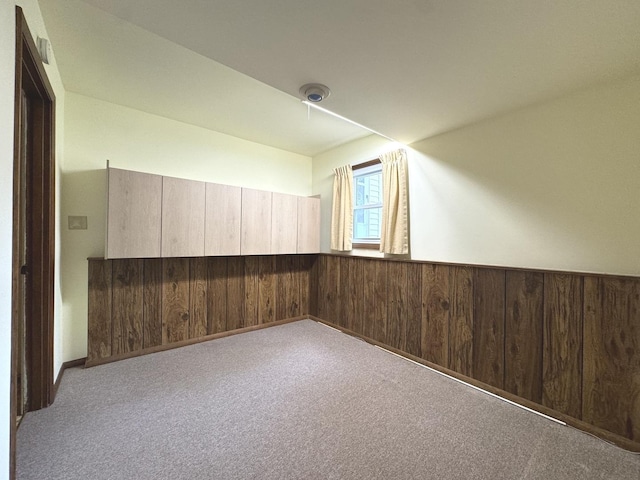 carpeted empty room with a wainscoted wall and wood walls