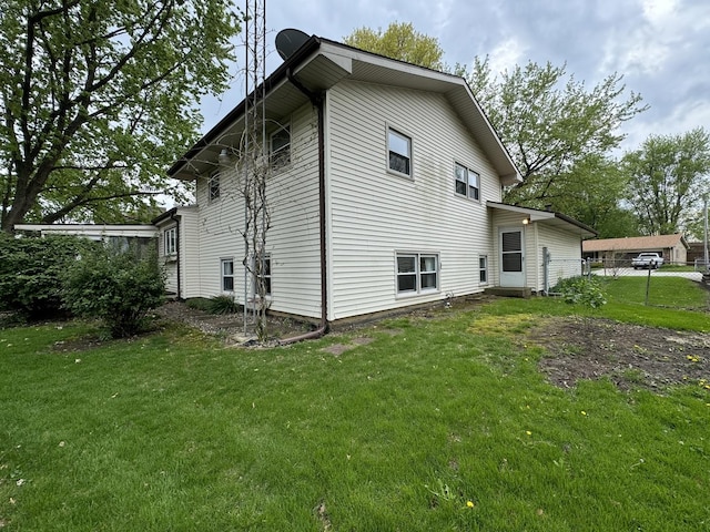 view of side of home with a lawn and fence