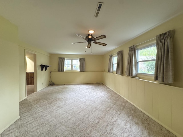 empty room with carpet flooring, baseboards, a ceiling fan, and visible vents