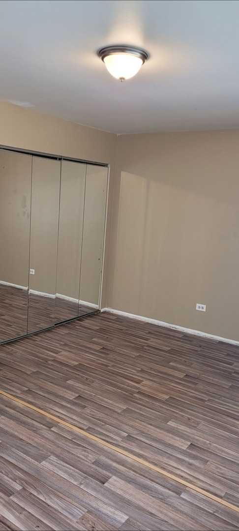 unfurnished bedroom with a closet, baseboards, and wood finished floors