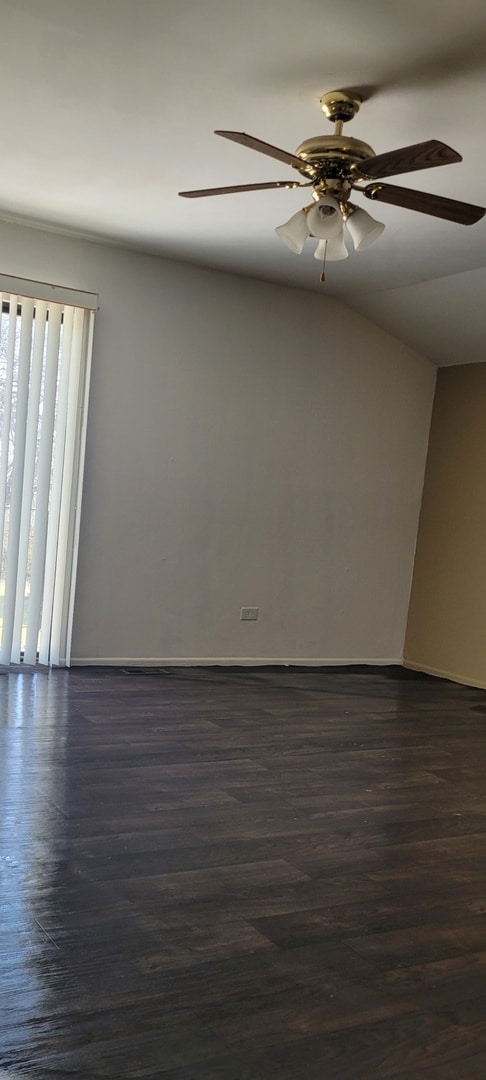 empty room featuring a ceiling fan, baseboards, and dark wood-type flooring