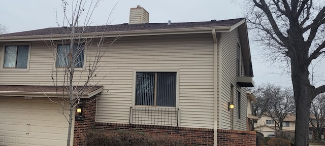 view of home's exterior featuring brick siding, an attached garage, and a chimney