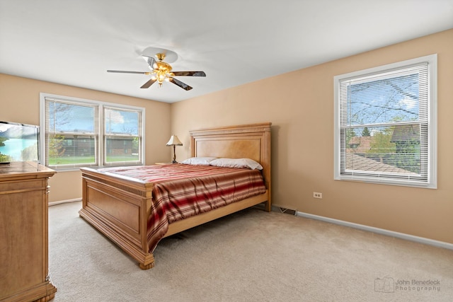bedroom featuring light colored carpet, baseboards, and ceiling fan