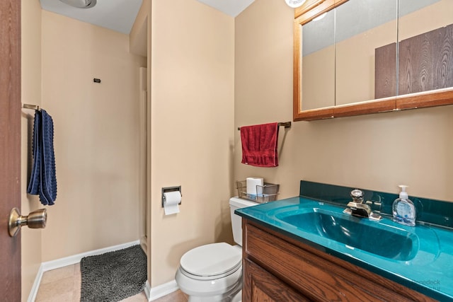 bathroom with toilet, baseboards, vanity, and tile patterned floors