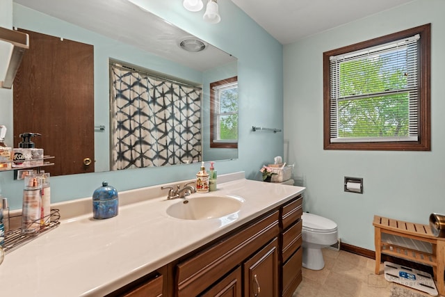 bathroom featuring plenty of natural light, toilet, vanity, and baseboards