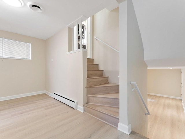 staircase with wood finished floors, baseboards, and a baseboard heating unit
