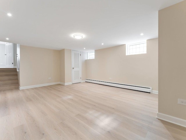 basement with light wood-style flooring, recessed lighting, a baseboard heating unit, baseboards, and stairs
