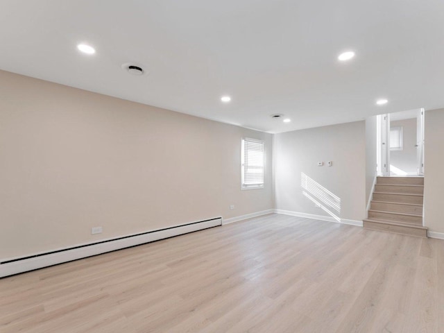 below grade area featuring light wood finished floors, a baseboard heating unit, and recessed lighting