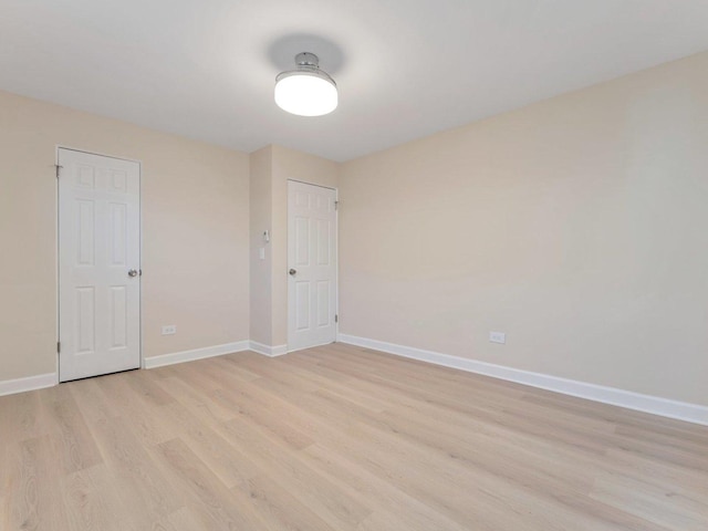 unfurnished room with baseboards and light wood-style floors