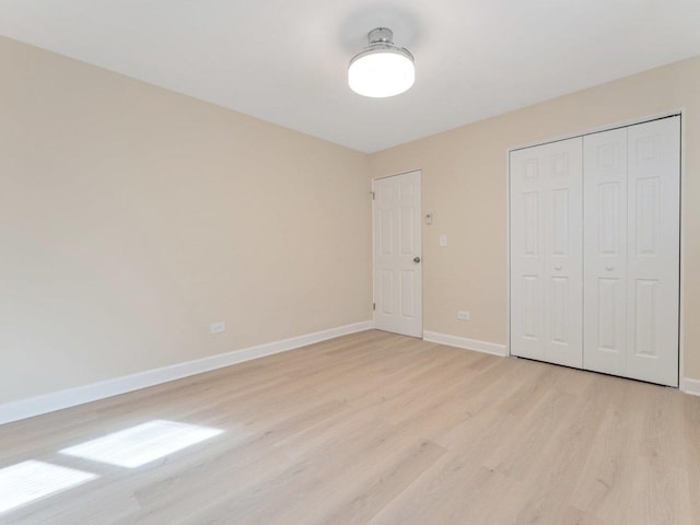 unfurnished bedroom featuring a closet, light wood-style floors, and baseboards