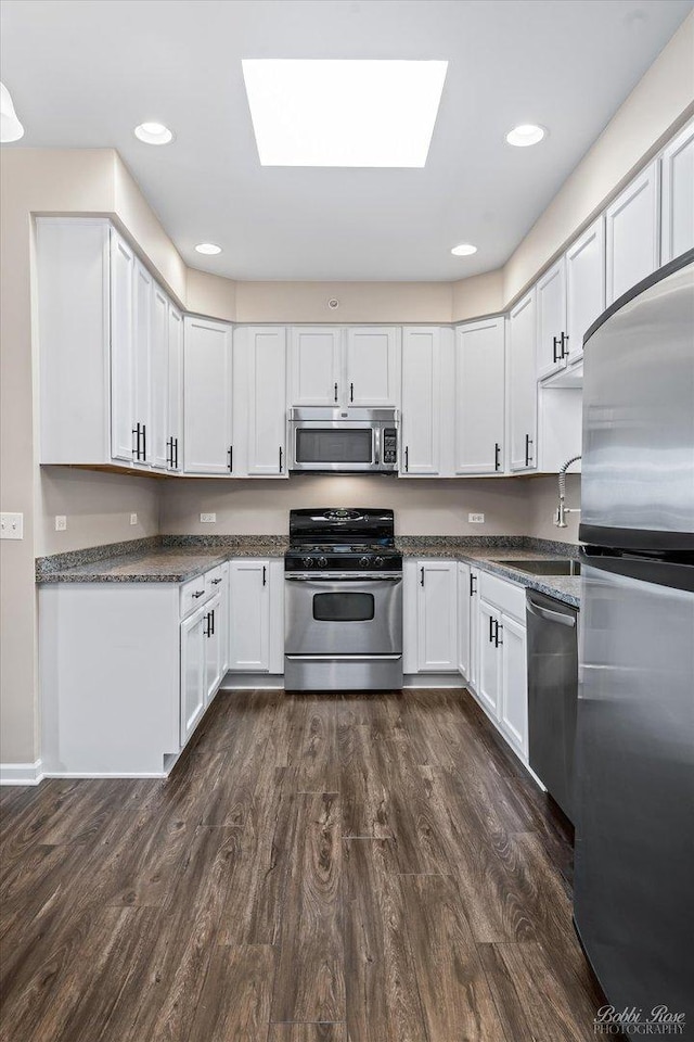 kitchen featuring white cabinets, stainless steel appliances, dark wood-type flooring, and a sink