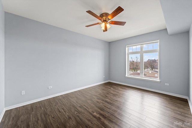 spare room featuring baseboards, a ceiling fan, and dark wood-style floors