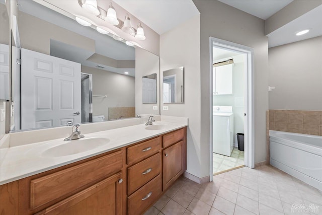 bathroom featuring tile patterned floors, a garden tub, washer / clothes dryer, and a sink