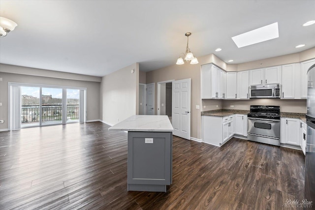 kitchen with a skylight, open floor plan, white cabinets, and appliances with stainless steel finishes
