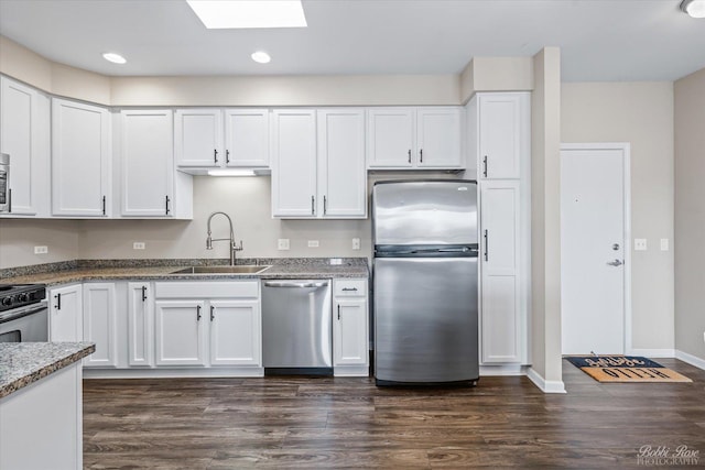 kitchen with a sink, a skylight, stainless steel appliances, dark wood-style flooring, and white cabinetry
