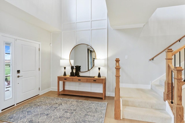 foyer with baseboards, wood finished floors, and stairway