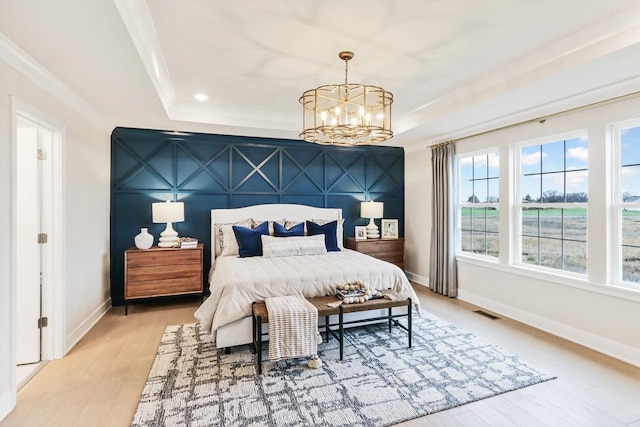 bedroom with visible vents, a raised ceiling, baseboards, a notable chandelier, and light wood-style floors