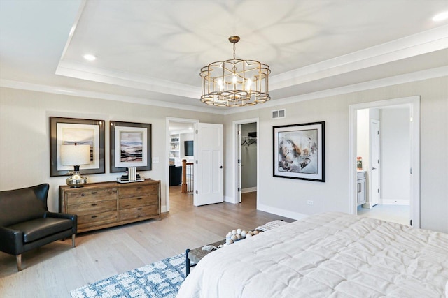 bedroom with an inviting chandelier, a tray ceiling, visible vents, and wood finished floors