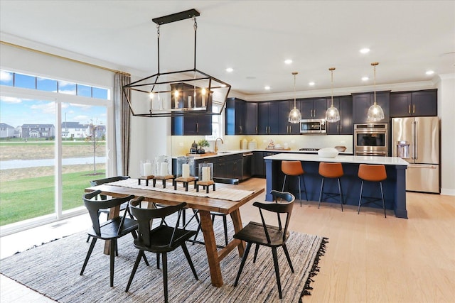 dining space featuring a notable chandelier, light wood-style flooring, recessed lighting, a water view, and ornamental molding