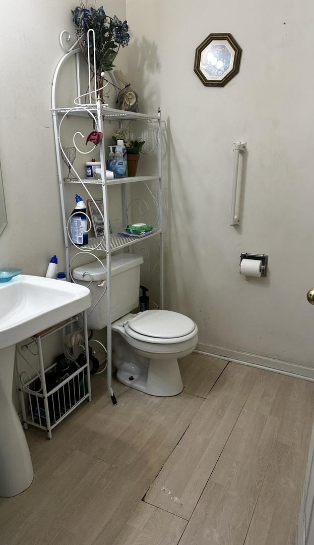half bathroom with toilet, baseboards, and wood finished floors