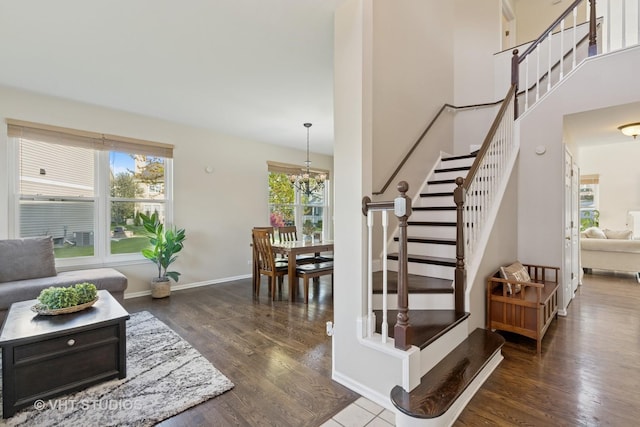 stairs with wood finished floors, a chandelier, and baseboards