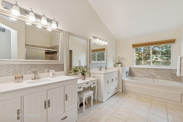 full bath with lofted ceiling, plenty of natural light, a stall shower, a garden tub, and two vanities