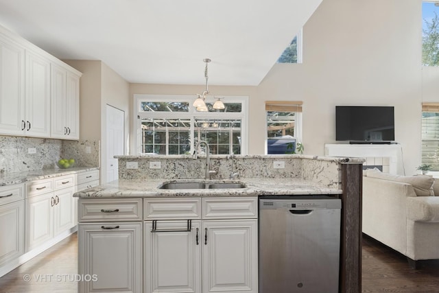 kitchen featuring dishwasher, a sink, open floor plan, tasteful backsplash, and white cabinetry