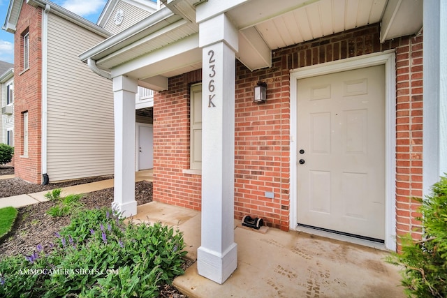 doorway to property with a porch and brick siding