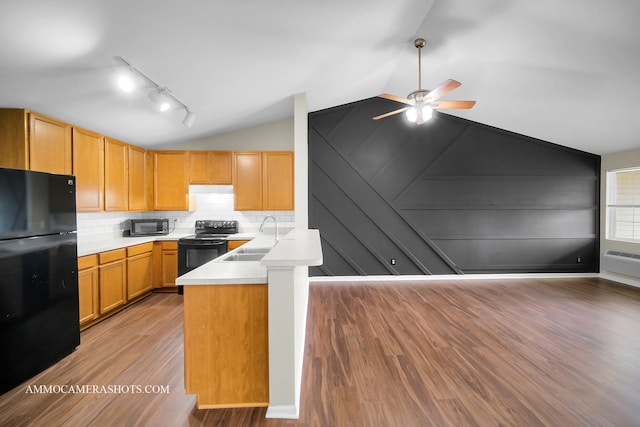kitchen featuring a peninsula, a sink, ceiling fan, black appliances, and vaulted ceiling