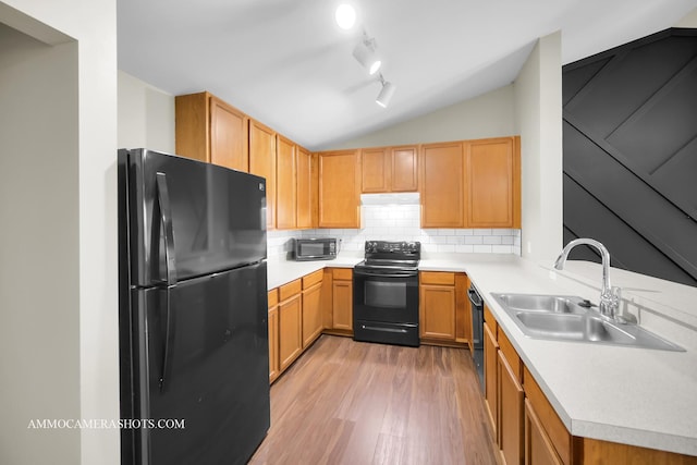 kitchen featuring a sink, black appliances, light countertops, tasteful backsplash, and light wood-type flooring