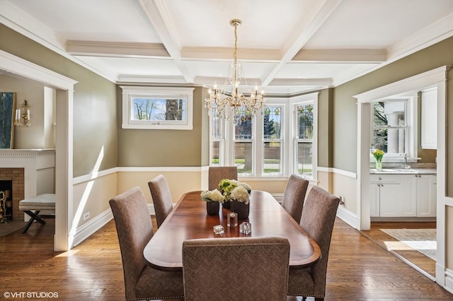 dining space with a chandelier, light wood finished floors, beam ceiling, baseboards, and coffered ceiling