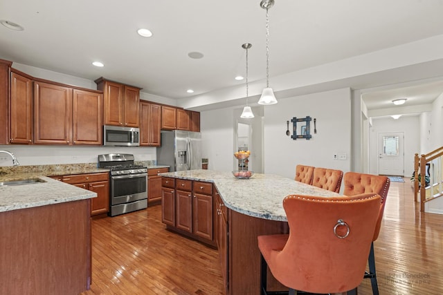 kitchen featuring hardwood / wood-style floors, appliances with stainless steel finishes, a sink, and a kitchen island
