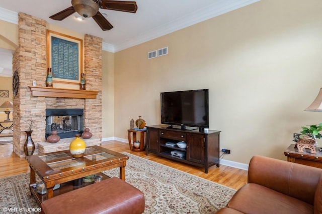 12116 Winterberry Ln, Plainfield, IL 60585 - living room featuring baseboards, a ceiling fan, ornamental molding, light wood-style flooring, and a stone fireplace