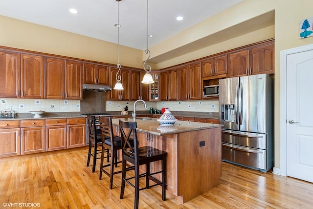 12116 Winterberry Ln, Plainfield, IL 60585 - kitchen with stainless steel appliances, under cabinet range hood, tasteful backsplash, a breakfast bar, and an island with sink