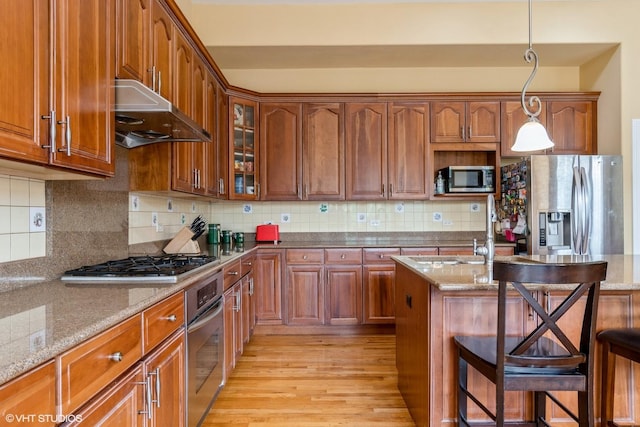 12116 Winterberry Ln, Plainfield, IL 60585 - kitchen with stainless steel appliances, ventilation hood, a kitchen breakfast bar, light wood-style floors, and light stone countertops