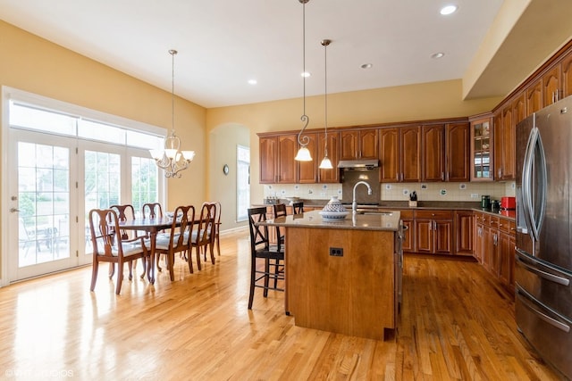 12116 Winterberry Ln, Plainfield, IL 60585 - kitchen with stainless steel refrigerator, under cabinet range hood, a breakfast bar, light wood-style floors, and decorative backsplash