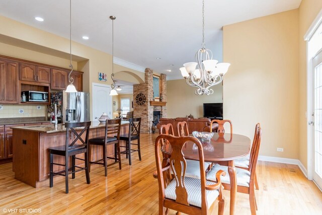 12116 Winterberry Ln, Plainfield, IL 60585 - dining room with a stone fireplace, light wood-style floors, arched walkways, a chandelier, and recessed lighting