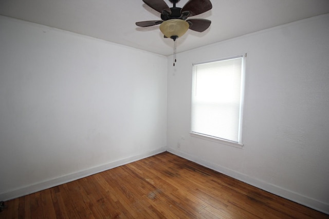 spare room featuring baseboards, wood-type flooring, and a ceiling fan